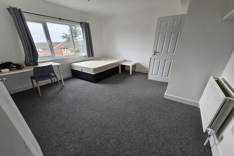 A spacious, bright bedroom featuring a large wi...