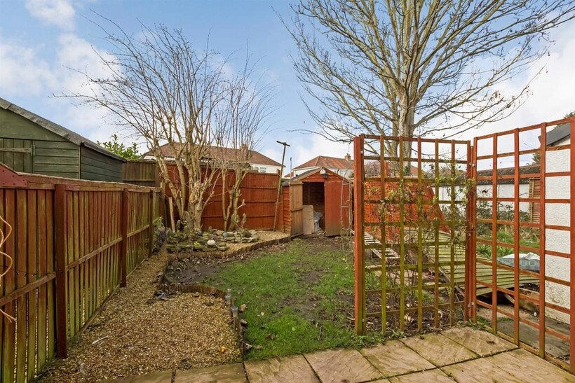 A charming garden space featuring a paved patio...