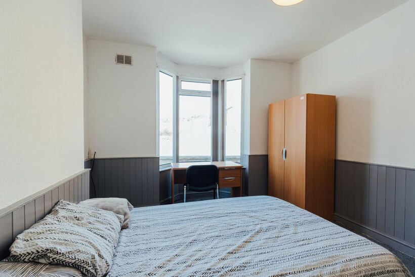 A well-lit double bedroom featuring a comfortab...