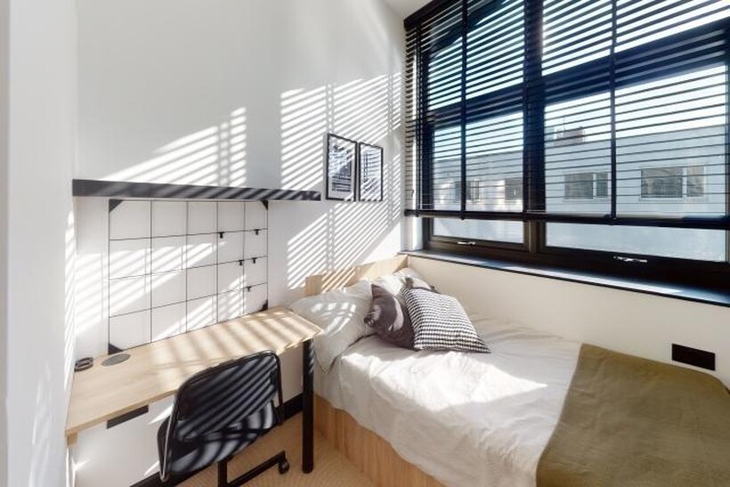 Bright, cozy bedroom featuring a large window w...