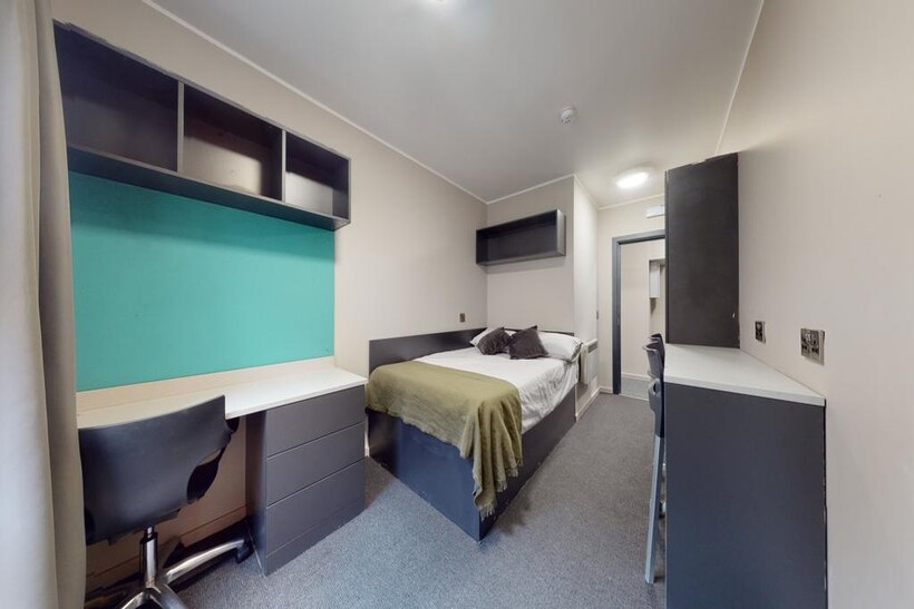 A cozy student bedroom featuring a comfortable ...