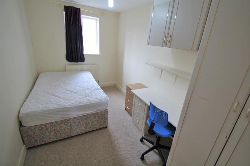 A small, clean bedroom with a single bed, a win...