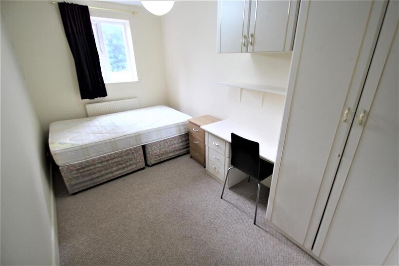 A bright and simple student bedroom featuring a...
