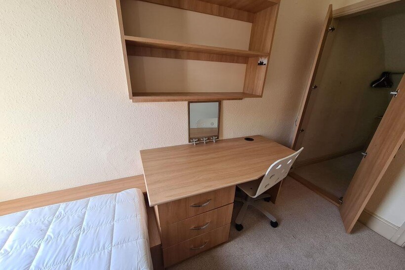 A neat and functional student bedroom featuring...