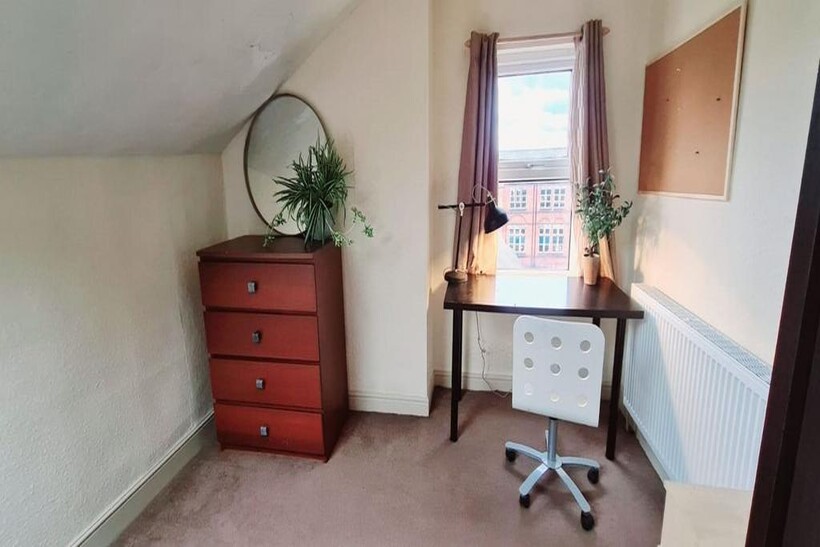 A cozy single bedroom featuring a neat workspac...