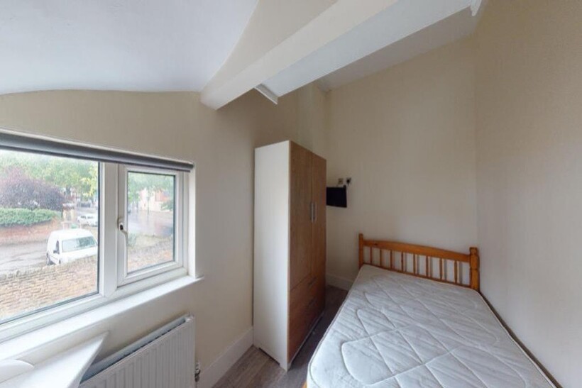 A cozy single bedroom featuring a wooden bed fr...