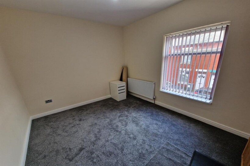 A small and clean room with carpeted flooring, ...