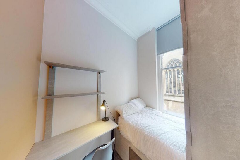 A tidy and well-lit single bedroom featuring a ...