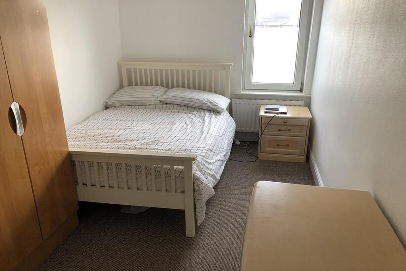 A tidy and simple bedroom featuring a white bed...