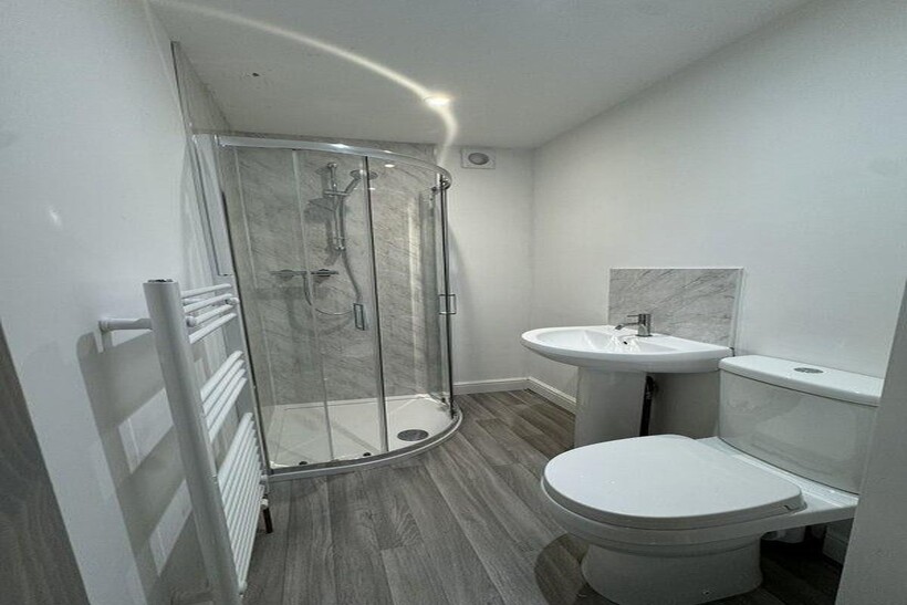 A modern bathroom featuring a curved glass show...