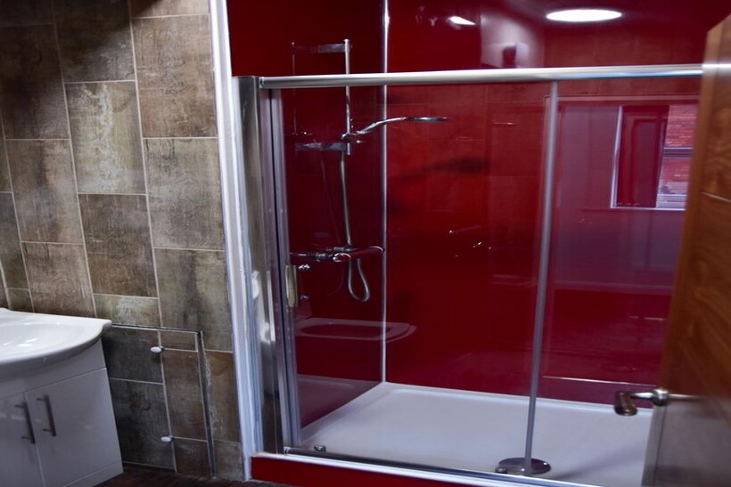 A modern bathroom with a vibrant red shower enc...