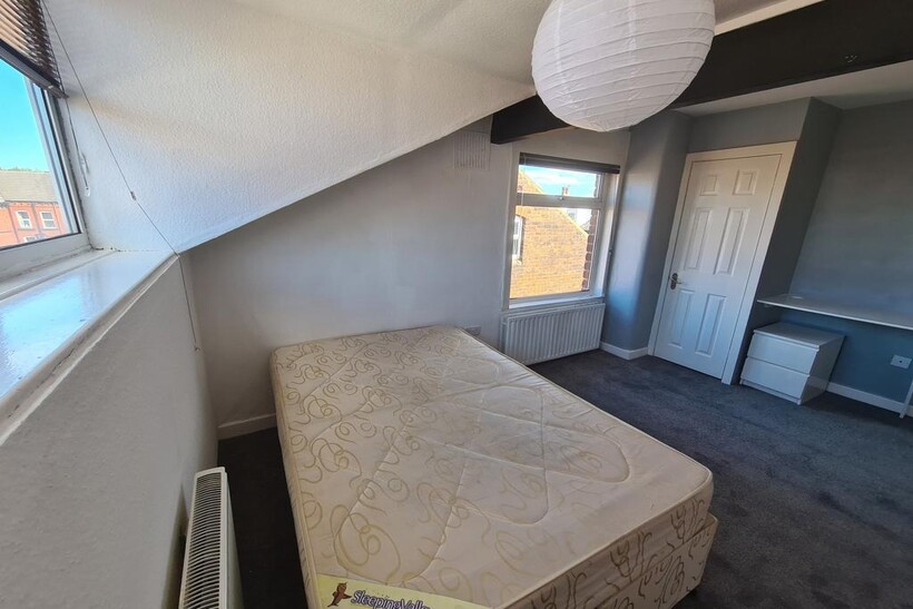 A cozy, well-lit single bedroom featuring a lar...