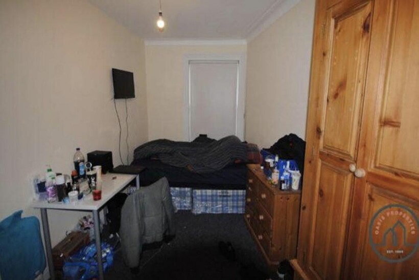 A modest single bedroom with a bed and some per...