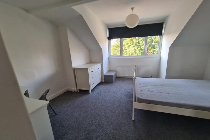 A bright and tidy bedroom featuring a large win...