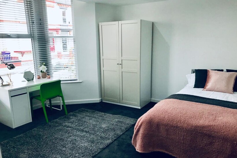 A bright and tidy bedroom featuring a bed with ...