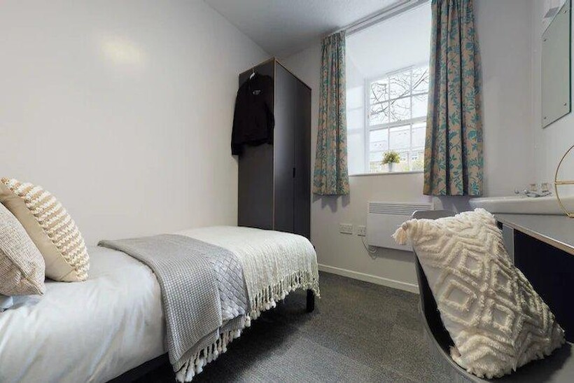 A comfortable single bedroom with a cozy bed, a...