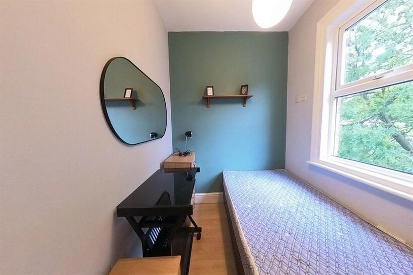 A cozy single bedroom with a large window that ...