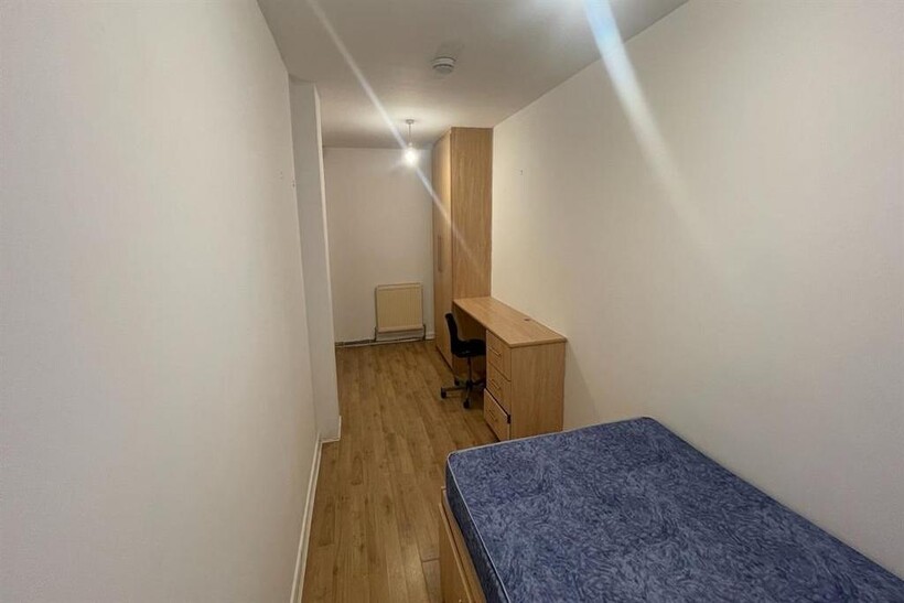 A tidy single bedroom featuring a single bed, a...