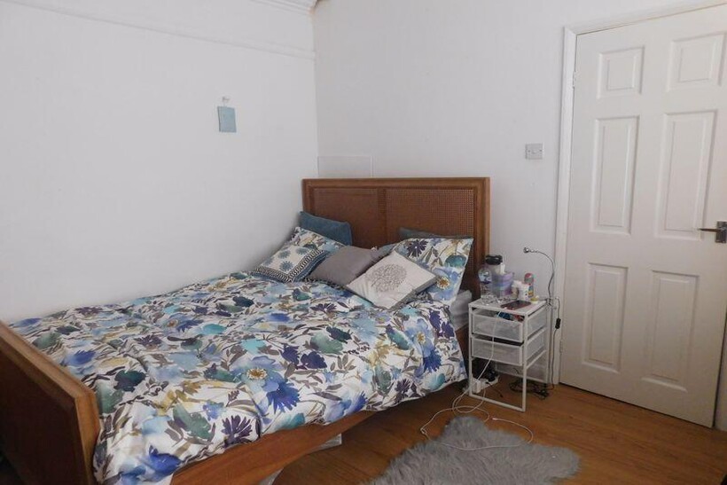 A cozy bedroom featuring a wooden bed frame wit...