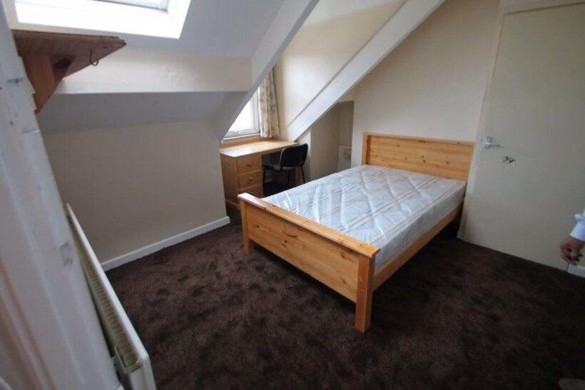 A cozy, well-lit bedroom featuring a wooden bed...