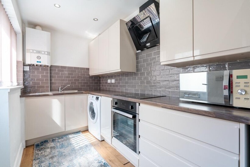 Modern kitchen with sleek white cabinetry, stai...