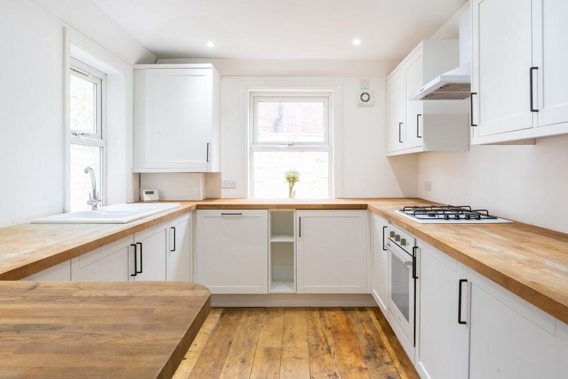 Bright and modern kitchen with white cabinets, ...