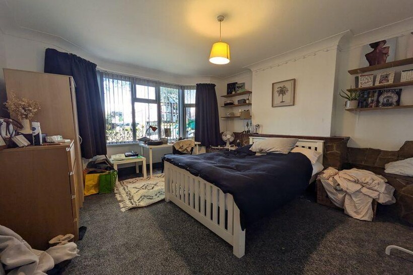 A cozy bedroom featuring a white bed frame with...