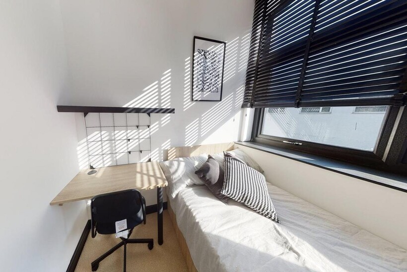 A bright and cozy single bedroom featuring a la...