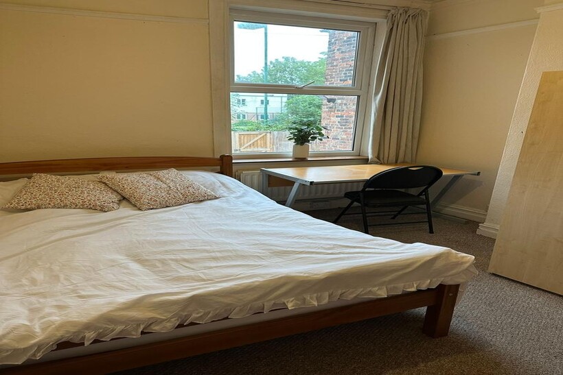 A cozy double bedroom featuring a wooden bed wi...