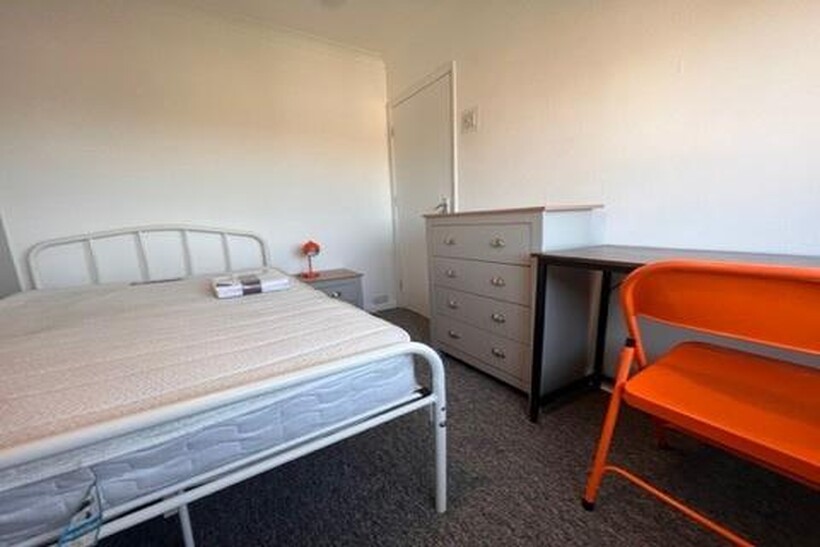 A cozy single bedroom featuring a simple metal ...