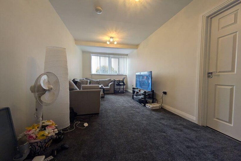 Bright, carpeted living room with a large windo...