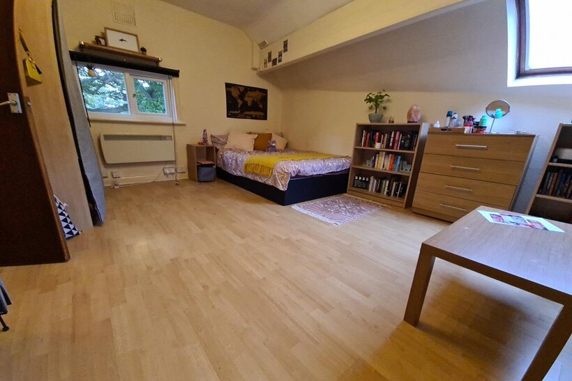Neat, well-kept bedroom with light wood floors,...