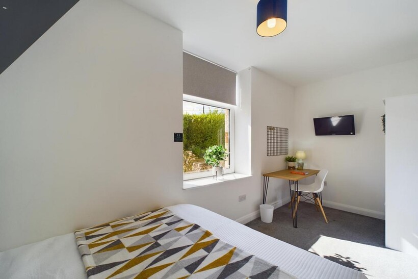 A bright and tidy bedroom featuring a comfortab...