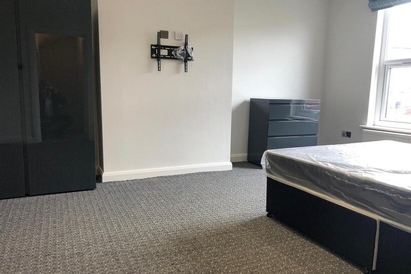 A modest single bedroom featuring a bed, window...