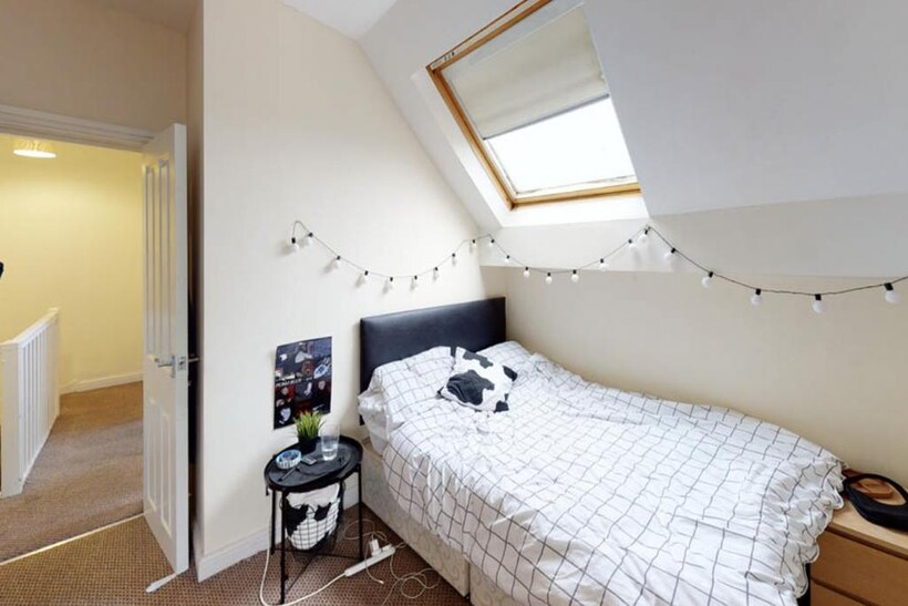 A cozy single bedroom featuring a neatly made b...