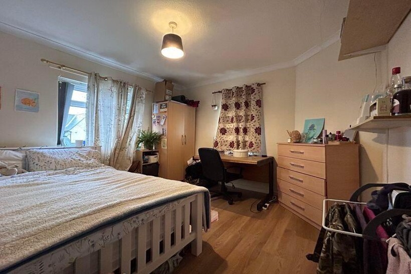 A cozy bedroom featuring a neatly made bed, a d...