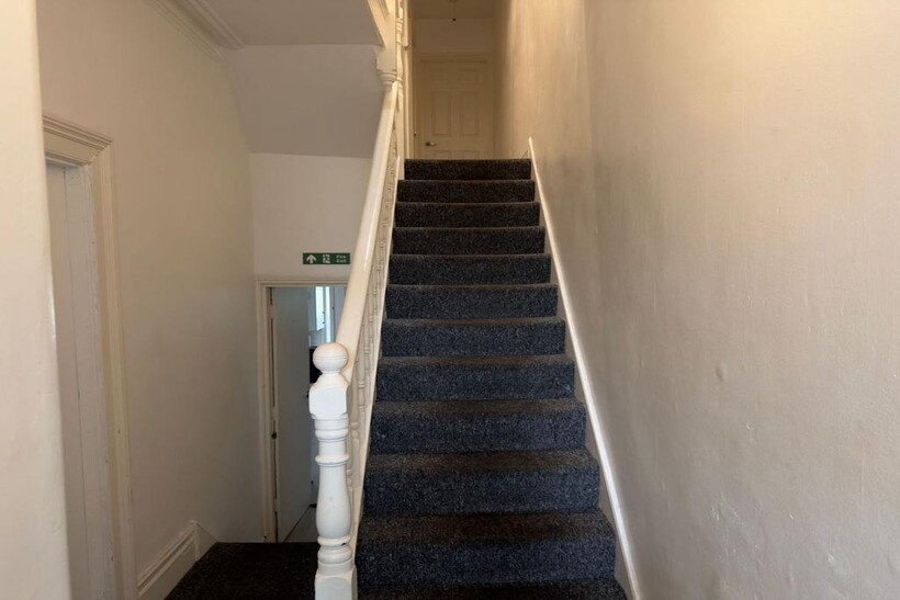 Carpeted staircase with a painted wooden balust...