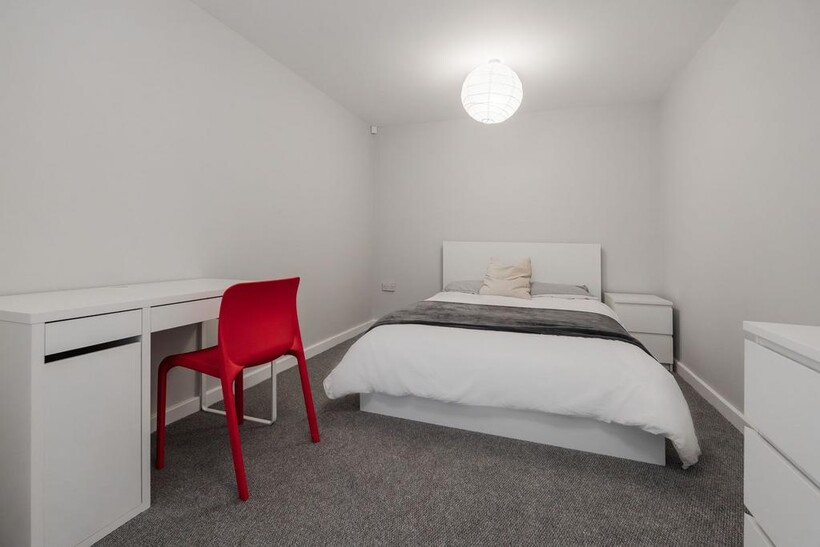 A clean, minimalist double bedroom featuring a ...
