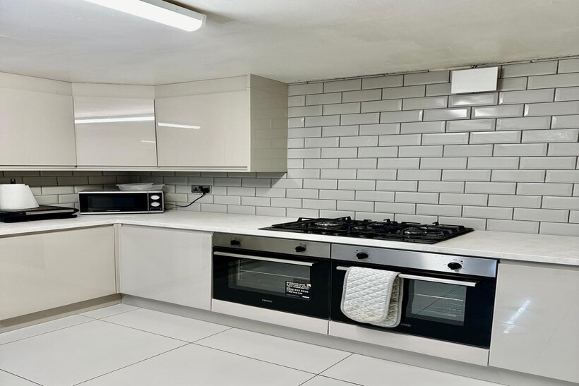 A clean and modern kitchen featuring white tile...