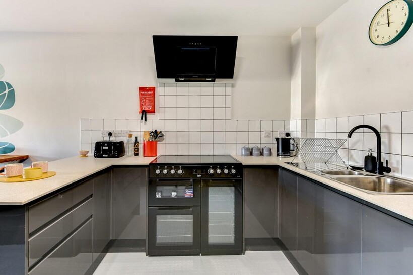 Modern U-shaped kitchen with glossy dark cabine...