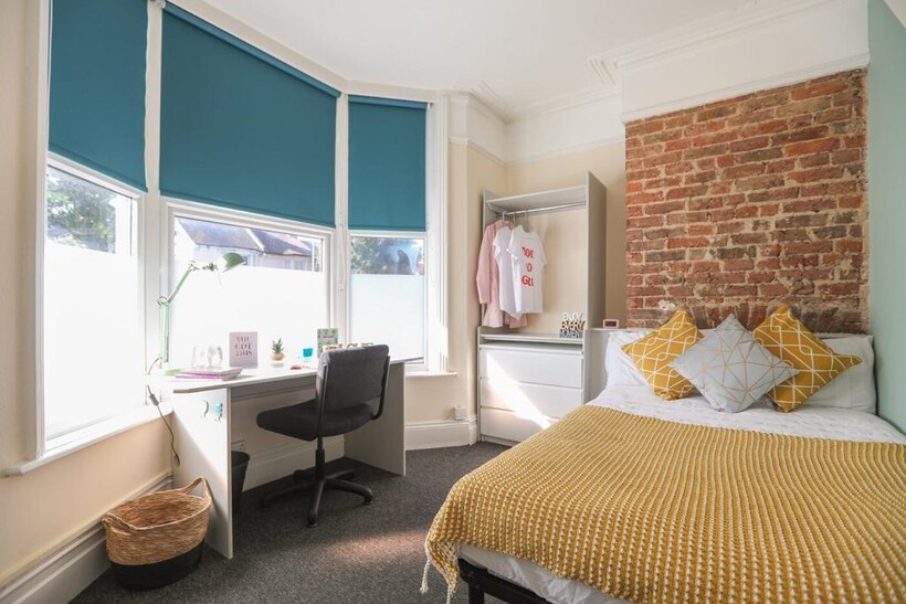 Bright and cozy bedroom featuring a comfortable...