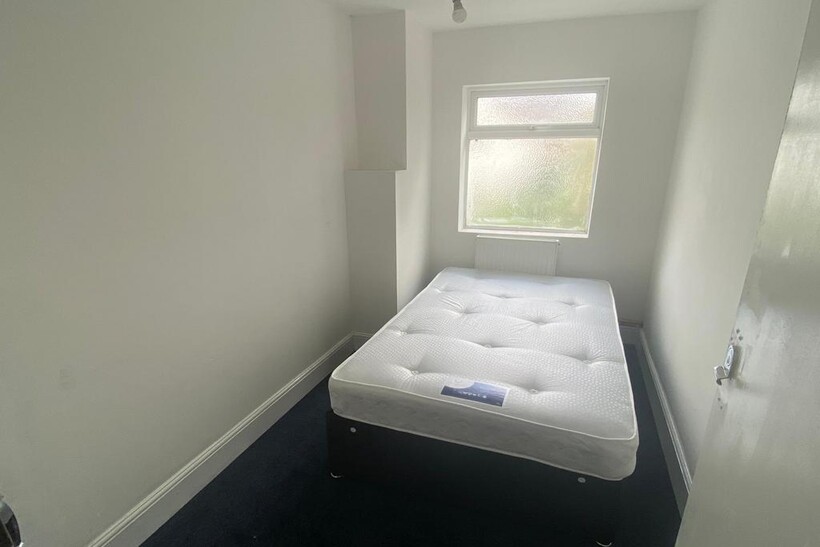 A compact single bedroom featuring a fresh, whi...