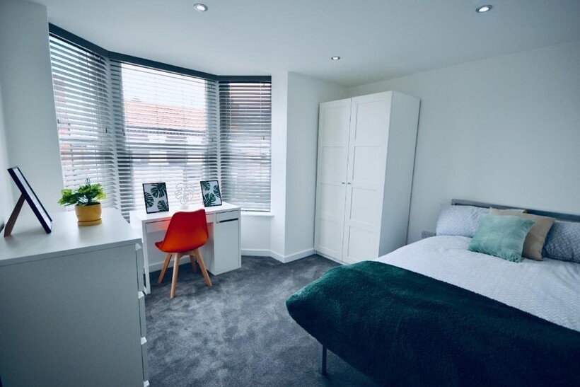 A bright and tidy bedroom featuring a large bed...