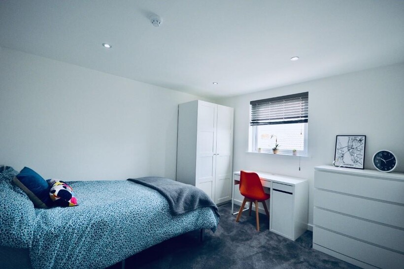 A bright and tidy bedroom featuring a cozy bed ...